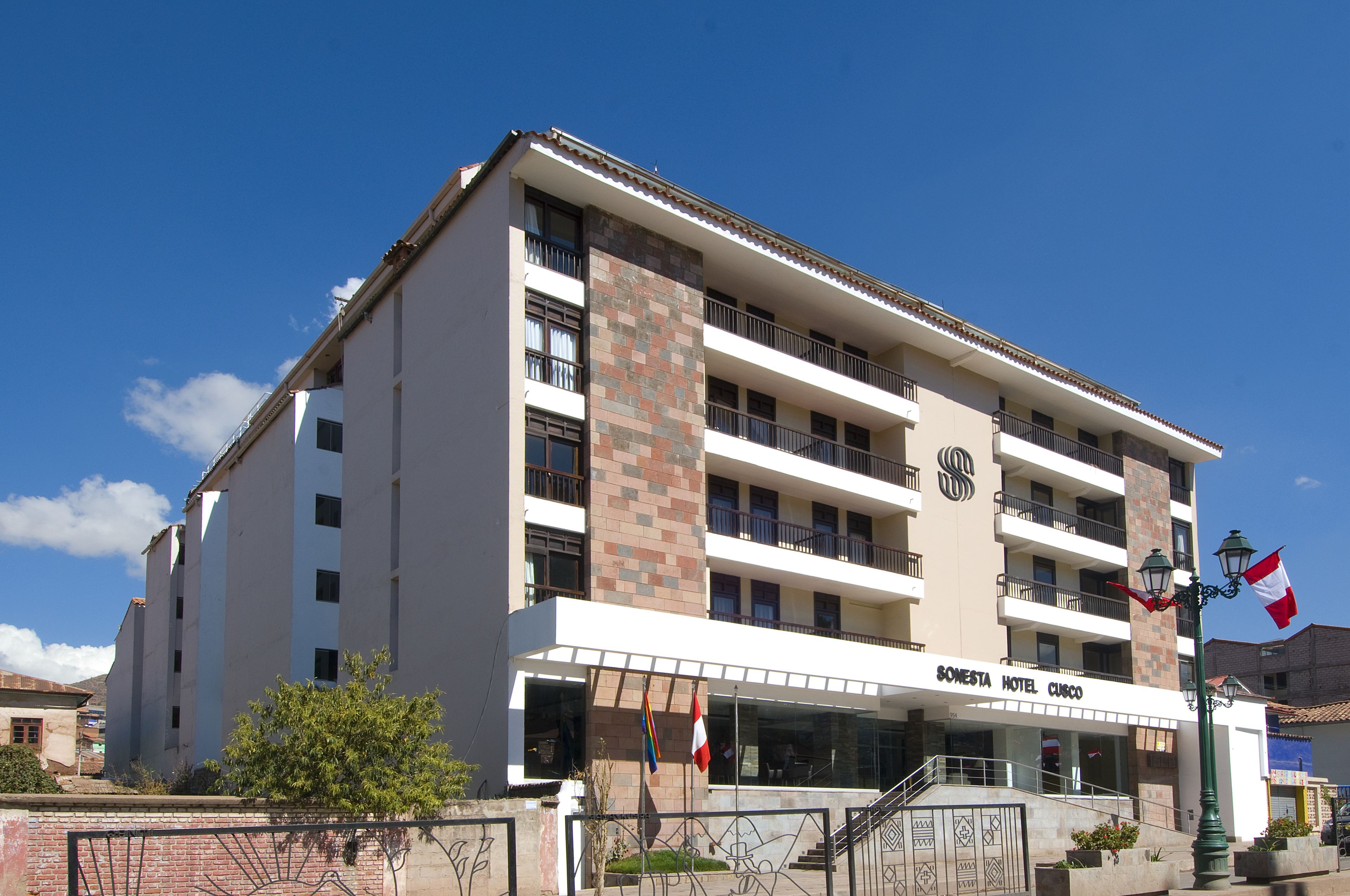 A multi-story hotel with a prominent entrance, balconies, and a flag.