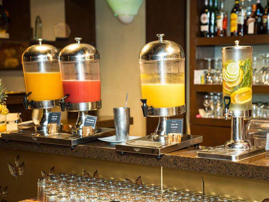 Una barra de jugos con tres dispensadores, cada uno con una bebida de color diferente.