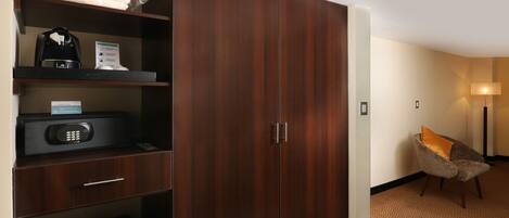 Habitación de hotel con armario, microondas, hervidor de agua y una silla.