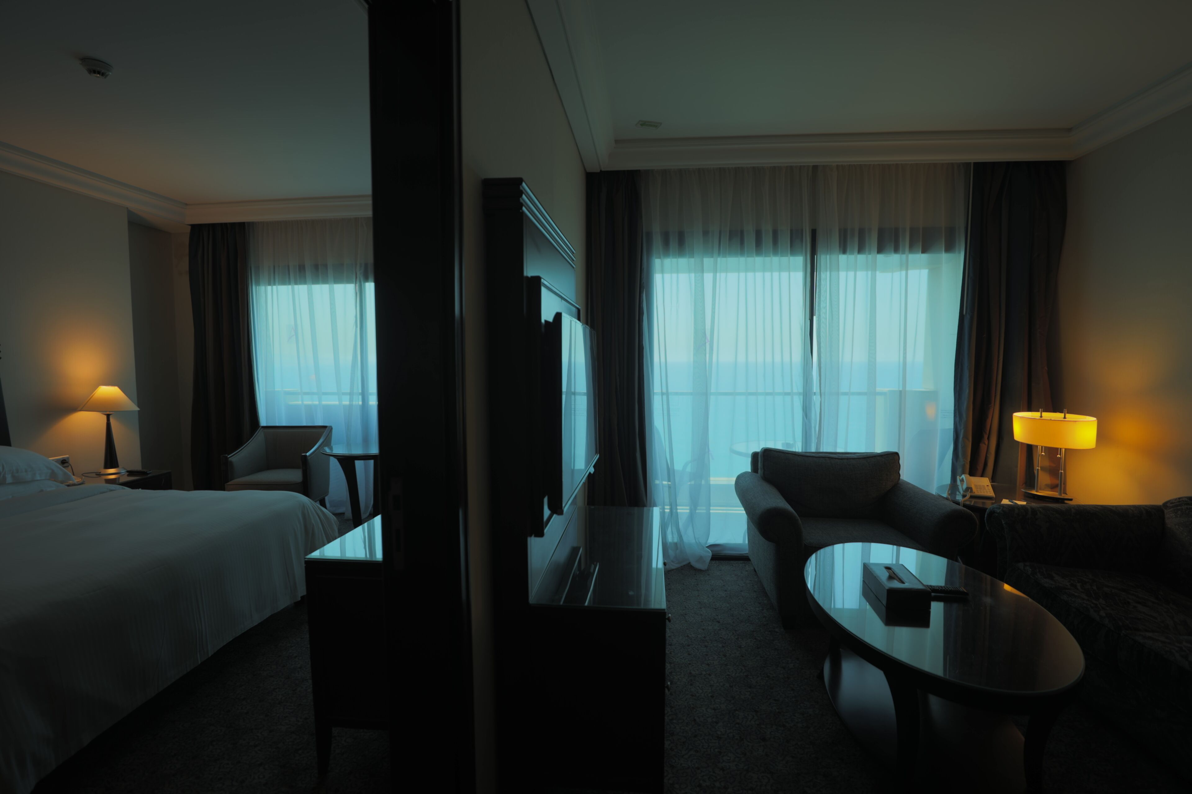 Una habitación de hotel con cama, sofá, mesa de centro y televisor.