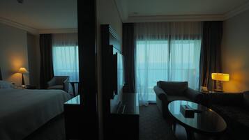 Una habitación de hotel con cama, sofá, mesa de centro y televisor.