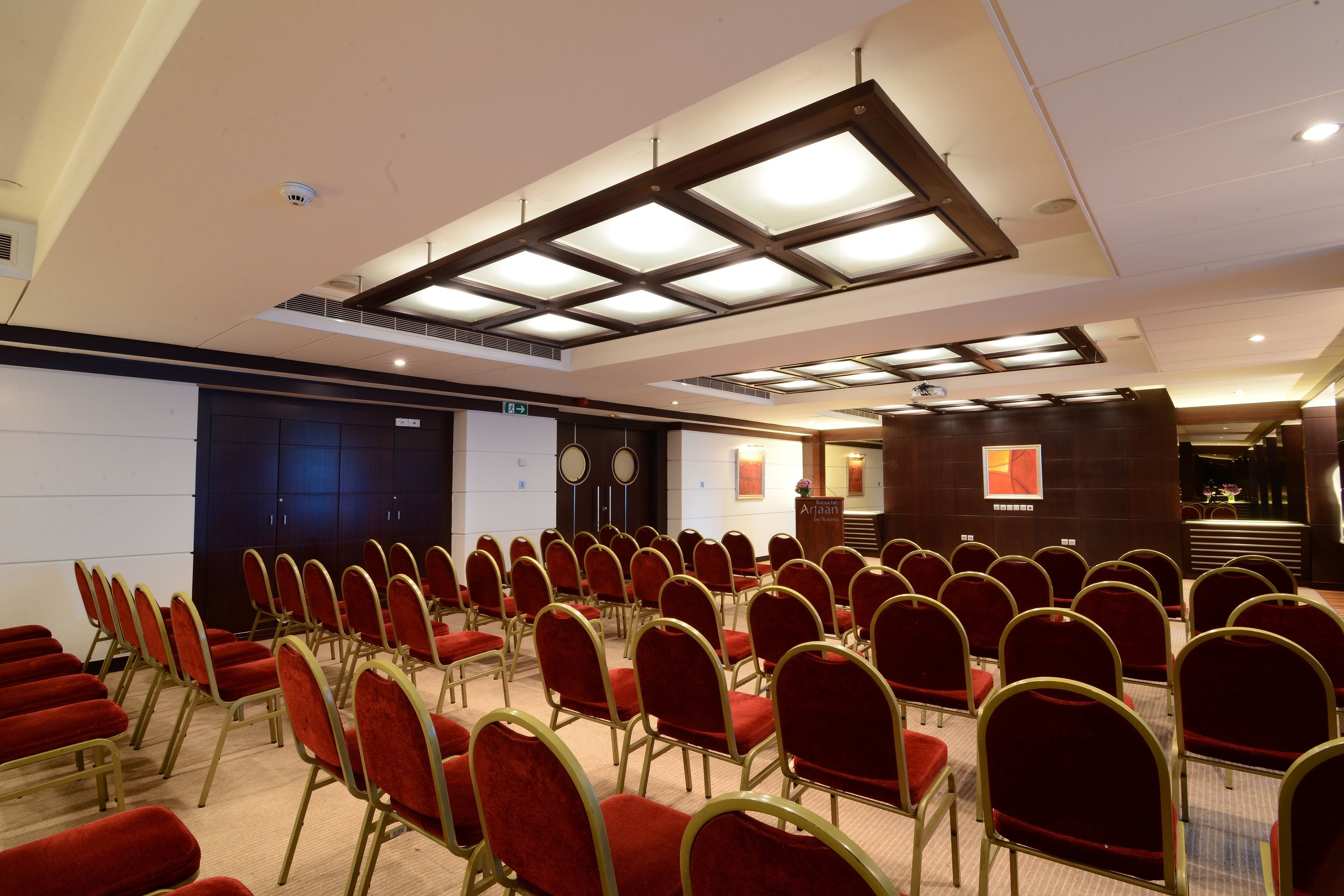 Un salón de conferencias con filas de sillas rojas y un atril al frente.