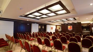 Un salón de conferencias con filas de sillas rojas y un atril al frente.