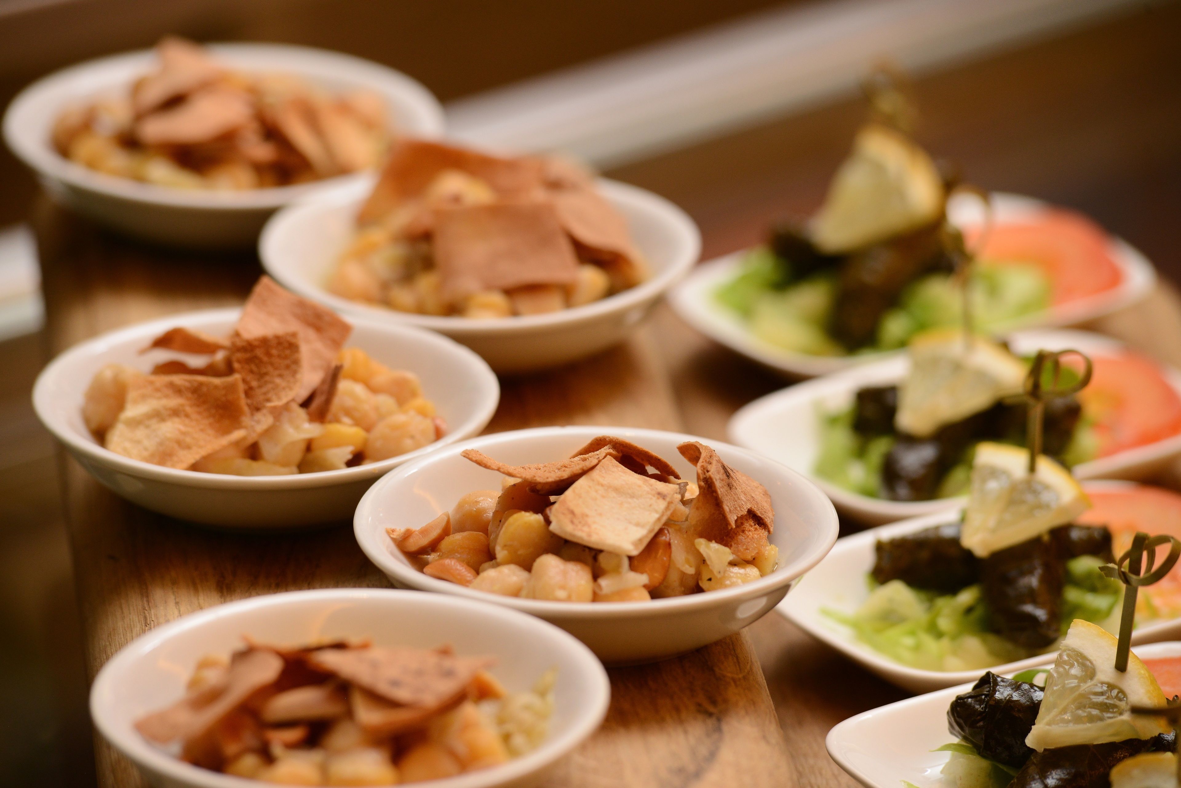 A variety of dishes including falafel, hummus, and stuffed grape leaves on a wooden table.