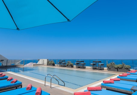 Una piscina al aire libre de temporada, sombrillas