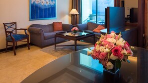 Een hotelkamer met een bank, fauteuil, bijzettafeltje en een bloemenvaas.