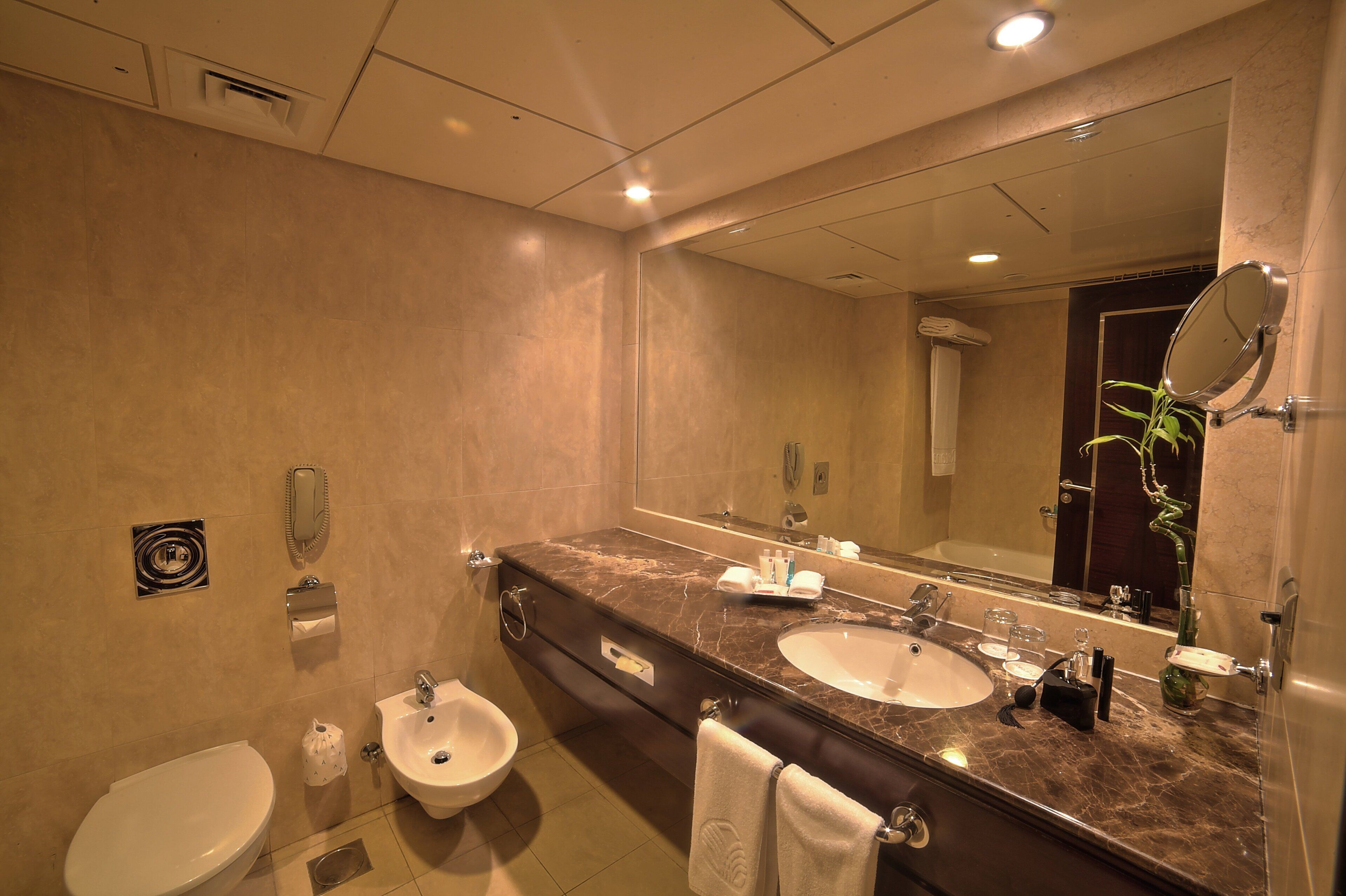Un baño moderno con un espejo grande, dos lavamanos, un inodoro y un bidé.
