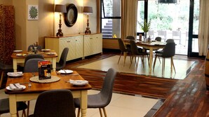 A dining area with wooden tables and chairs, a buffet setup, and a view of the outdoors through large windows. - Sandton Lodge Rivonia (Sandton)