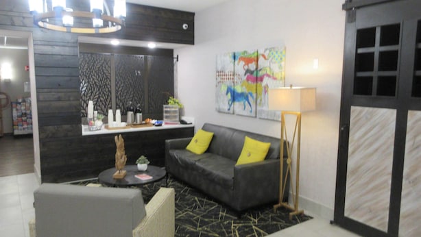 A modern living room with a grey sofa, a small round table, and a decorative plant. - Best Western Decatur Inn (Decatur)