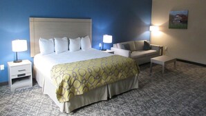 A hotel room with a large bed, a sofa, a small table, and two bedside lamps. - Best Western Decatur Inn (Decatur)