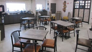 A restaurant with multiple tables and chairs, a kitchen area, and a decorative wall piece. - Best Western Decatur Inn (Decatur)