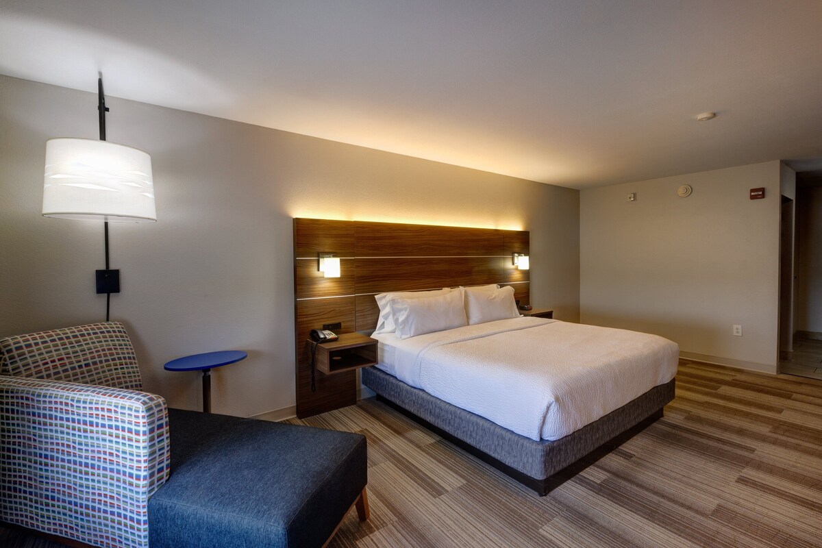 Une chambre d’hôtel avec un lit, un bureau, une chaise et une lampe.