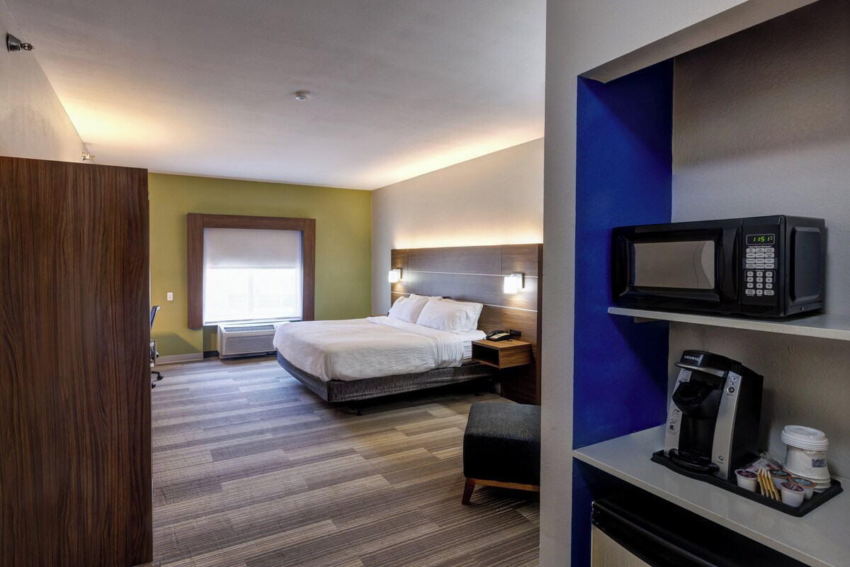 Une chambre d’hôtel équipée d’un lit, d’une table de chevet, d’un four à micro-ondes, d’une machine à café et d’un petit coin salon.