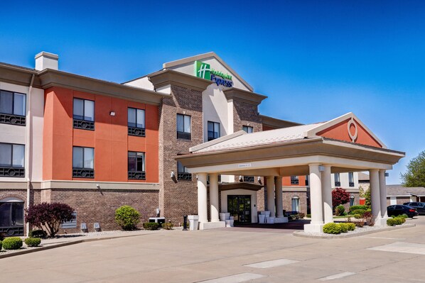 Um hotel Holiday Inn Express com fachada de tijolos, entrada coberta e estacionamento.