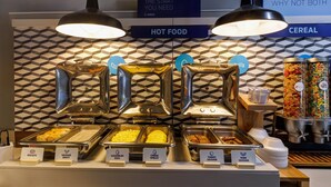A buffet with labeled food sections including biscuits, sausage gravy, scrambled eggs, cheese omelet, turkey sausage, and pork sausage.