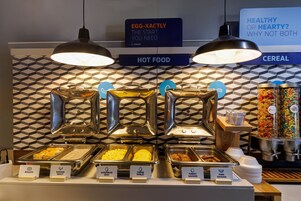 A buffet with labeled food sections including biscuits, sausage gravy, scrambled eggs, cheese omelet, turkey sausage, and pork sausage.