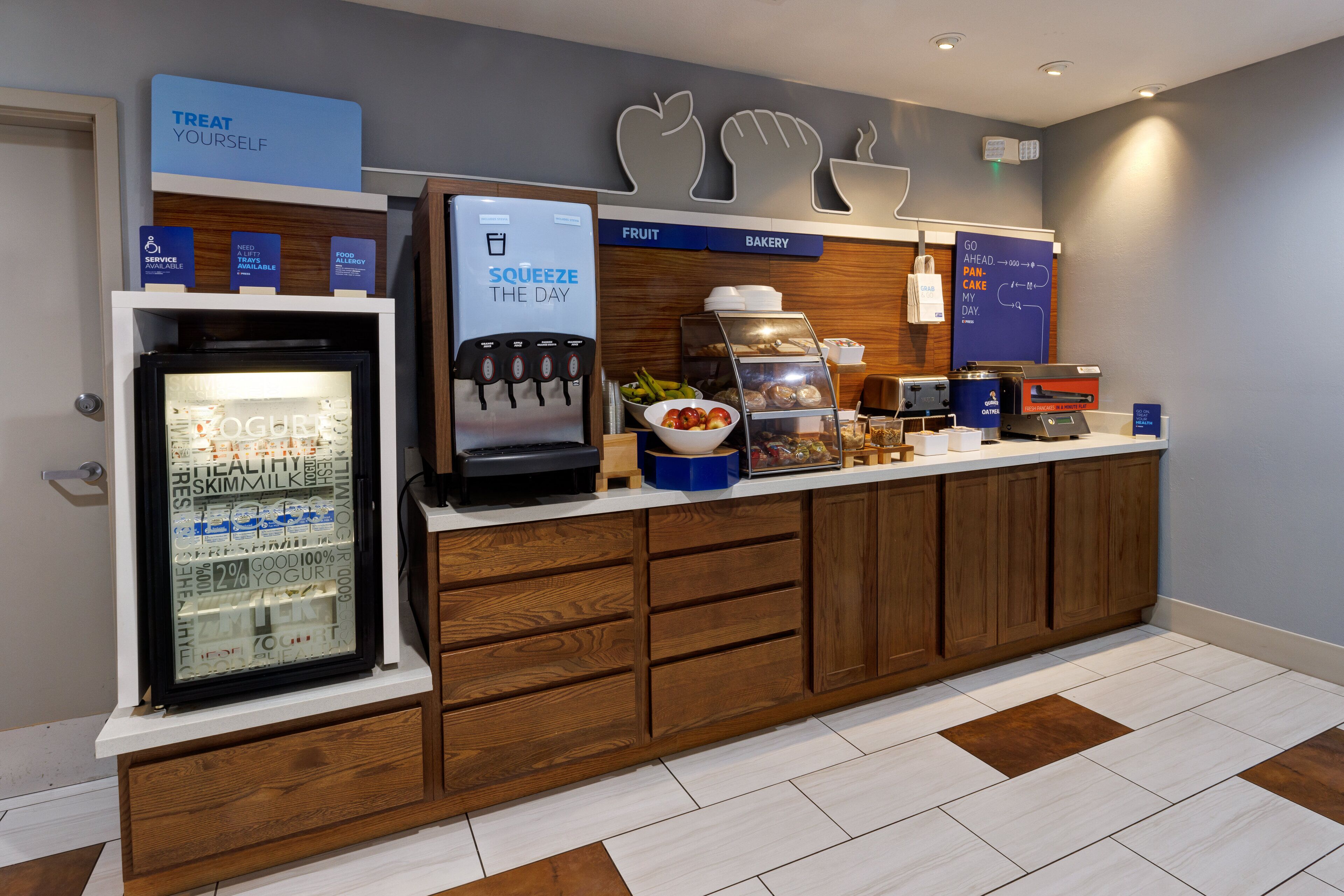 A self-service breakfast area with a yogurt dispenser, a coffee machine, and a fruit and bakery section.