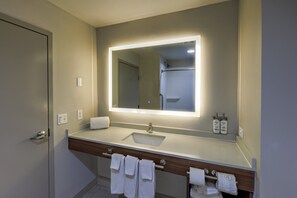 A bathroom with a sink, mirror, towel rack, and a shower area.