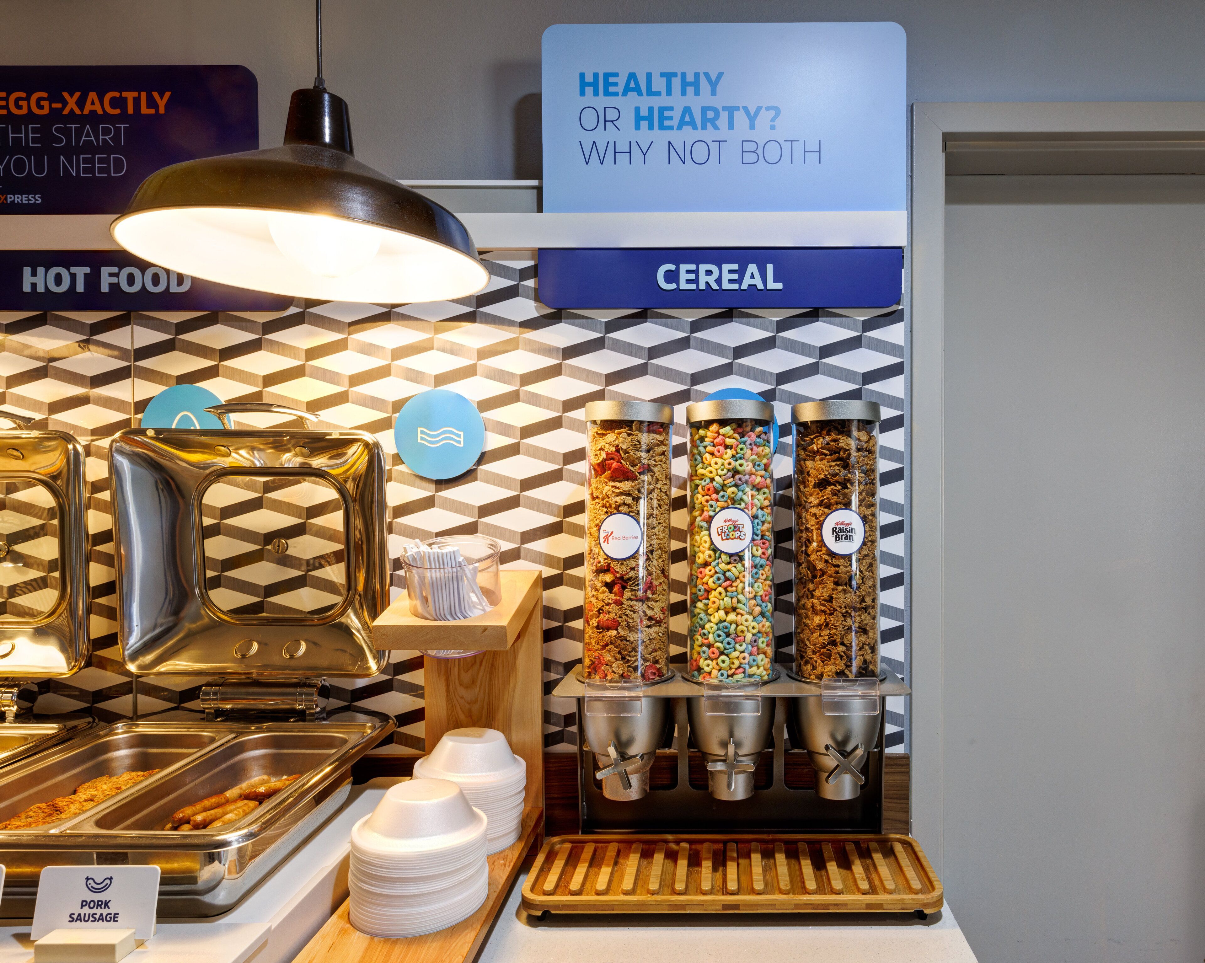 A buffet area with labeled food stations including hot food, cereal, and a sign promoting healthy eating.