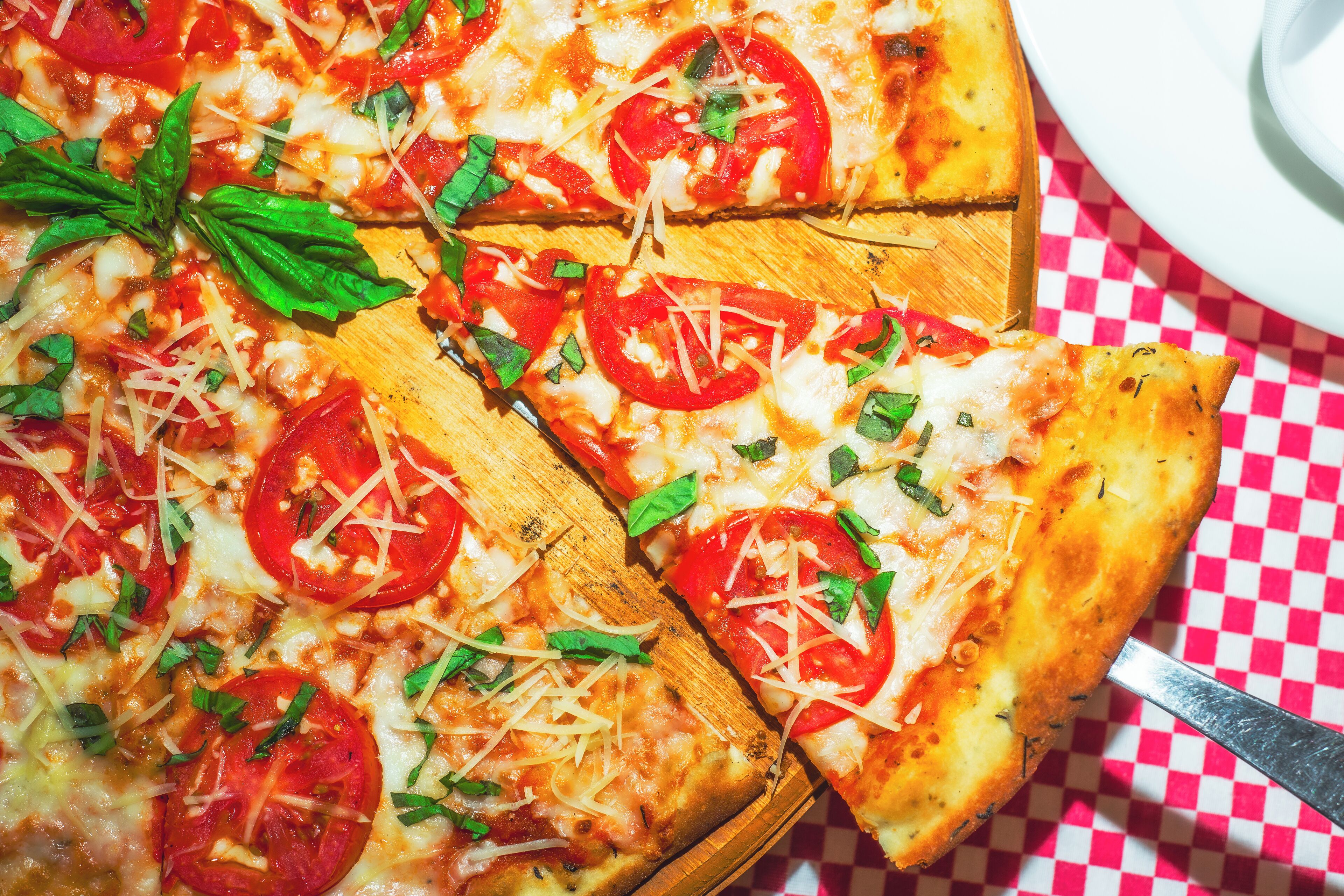 A pizza with tomato slices and cheese on a wooden board.