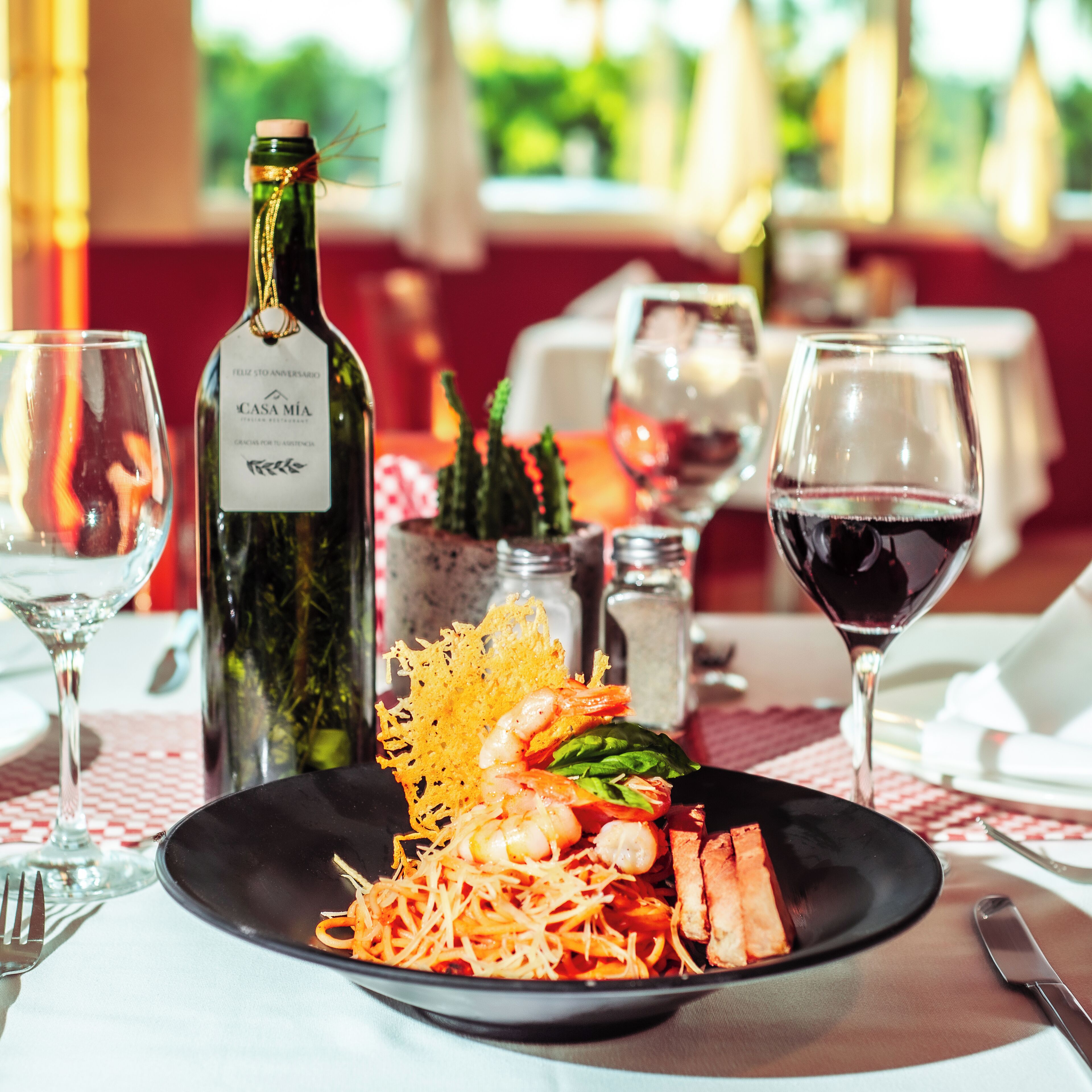 A dining table with a plate of food, a bottle of wine, and glasses.