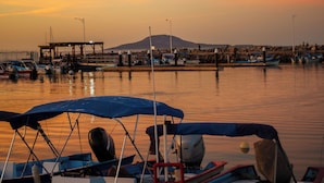Una marina con barcos amarrados, un muelle y una montaña al fondo.