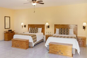 Habitación de hotel con dos camas, cabeceros de madera, mesitas de noche y un ventilador de techo.