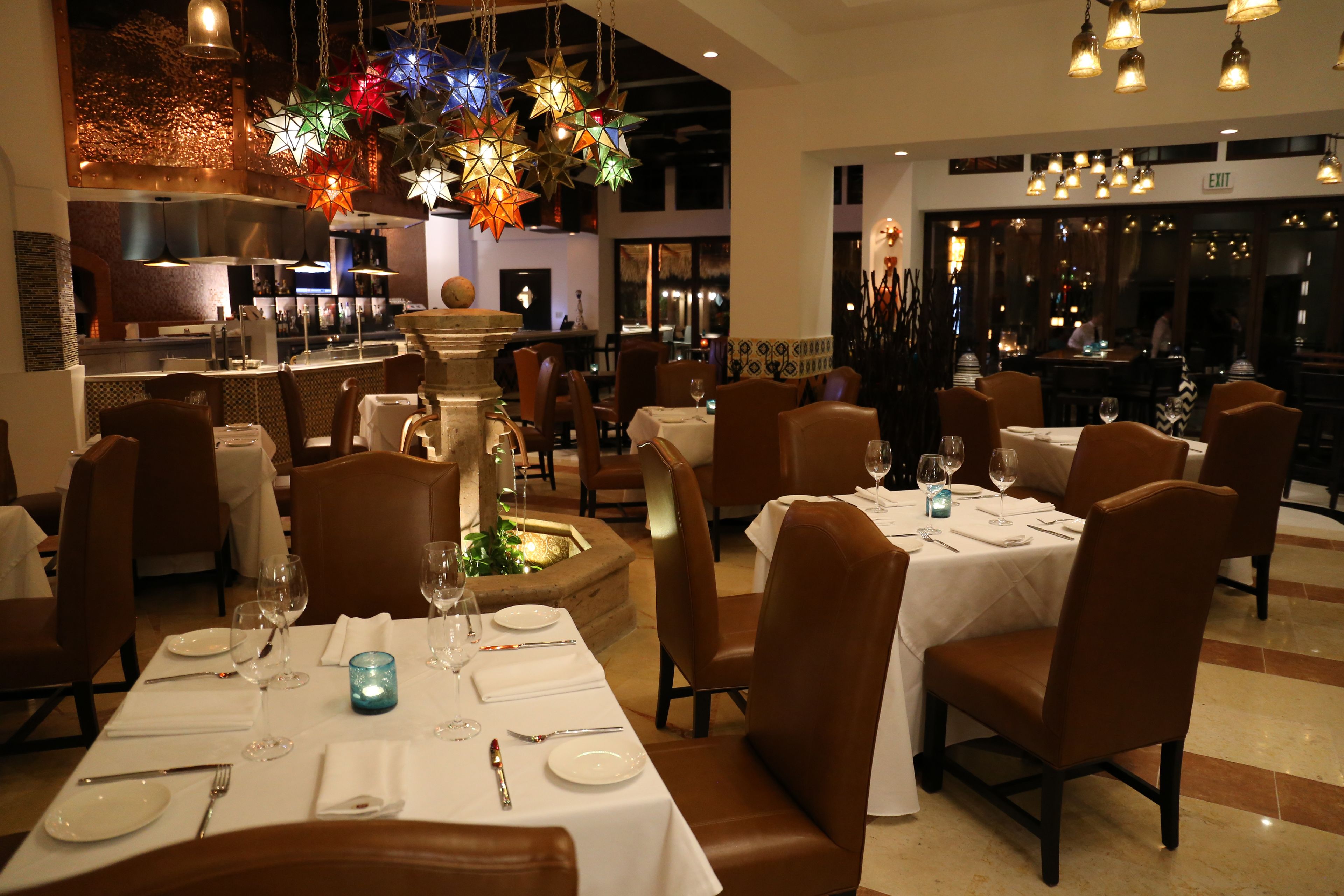 A restaurant with multiple dining tables set for guests, each with white tablecloths, wine glasses, and cutlery.