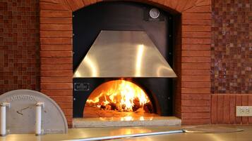 Horno de pizza de ladrillo con pantalla digital y pala para pizza.