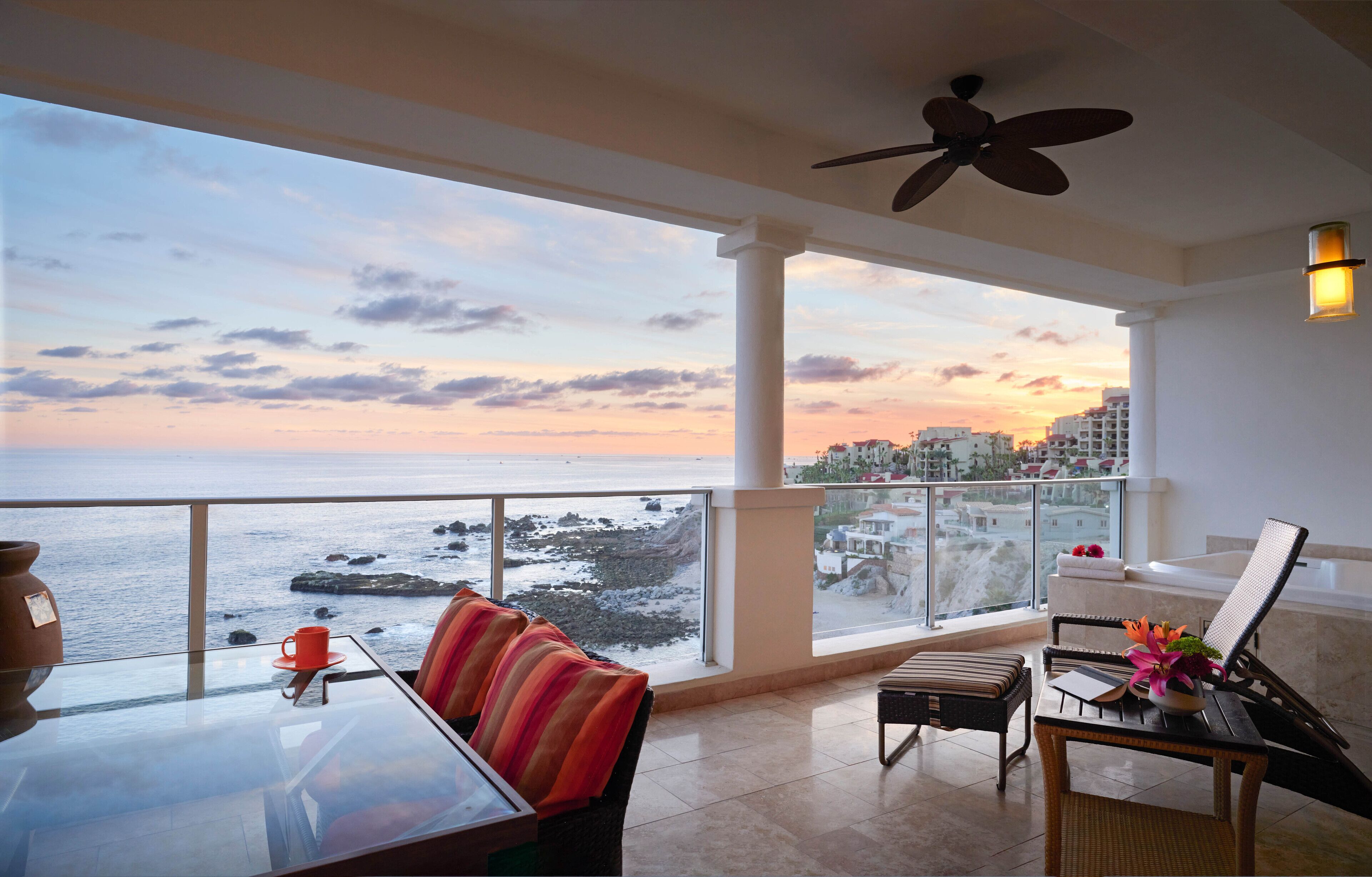 Un balcón con vista al mar y al paisaje urbano al atardecer.