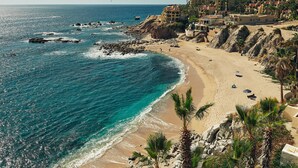 Un hotel sul lungomare con vista sulla spiaggia, costa rocciosa e palme.