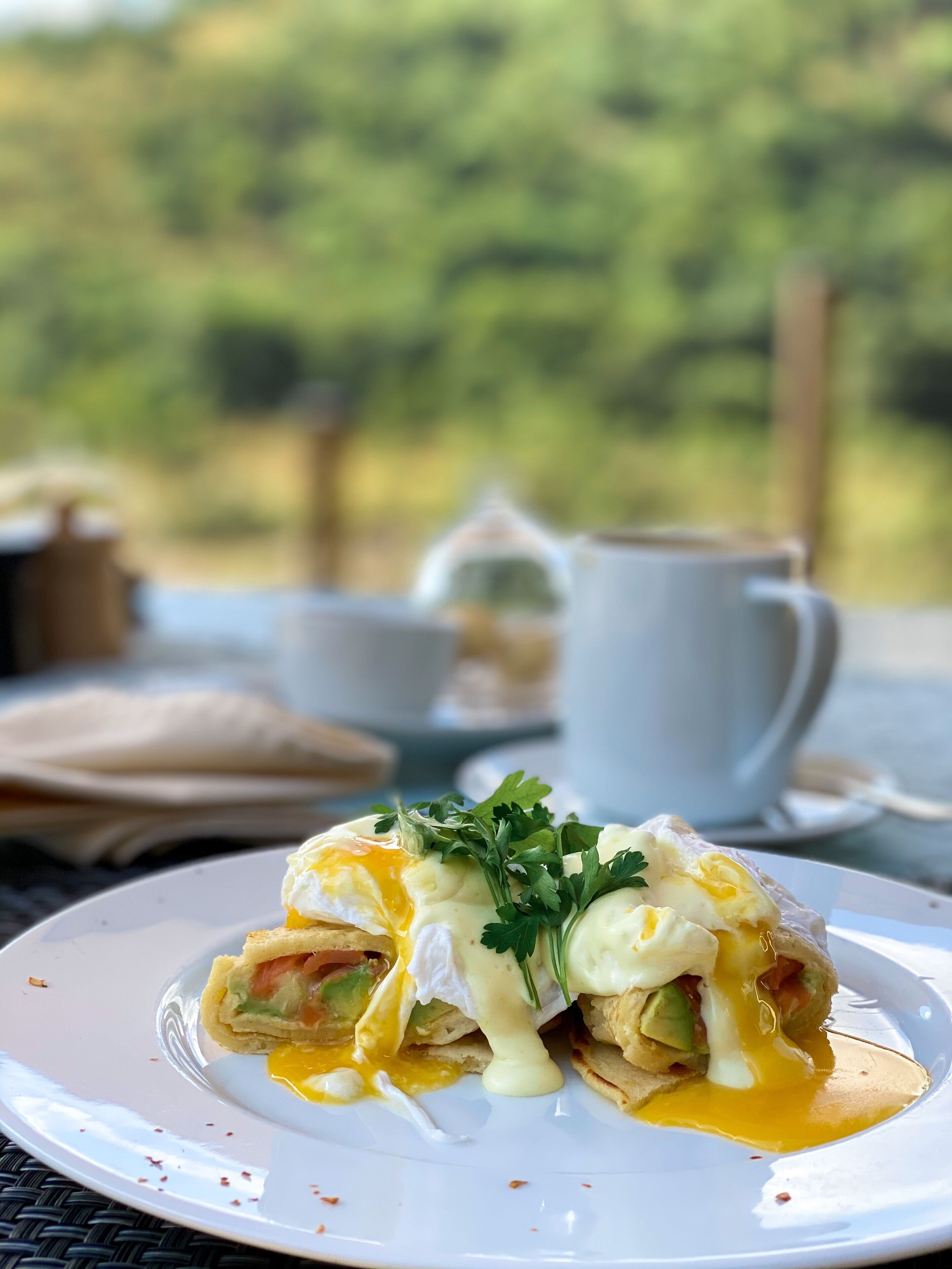 A breakfast dish with poached eggs, avocado, and greens on a white plate.