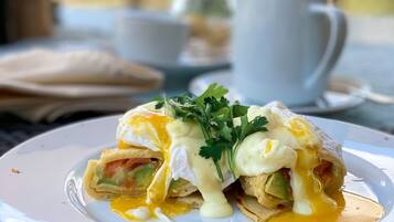 A breakfast dish with poached eggs, avocado, and greens on a white plate.