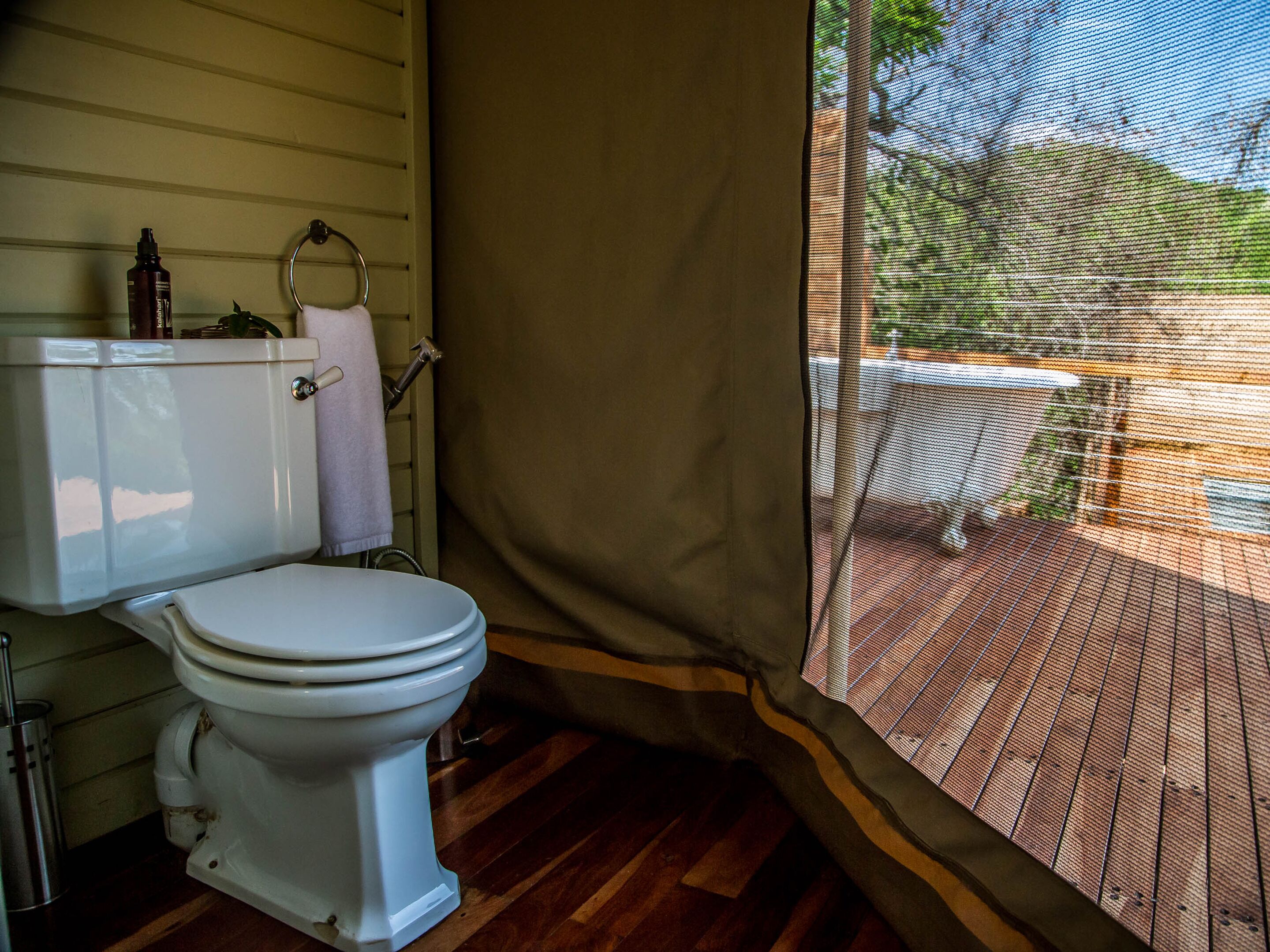 Un baño con inodoro, cortina de ducha y ventana con vistas a una terraza.