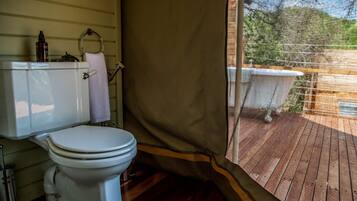 Un baño con inodoro, cortina de ducha y ventana con vistas a una terraza.