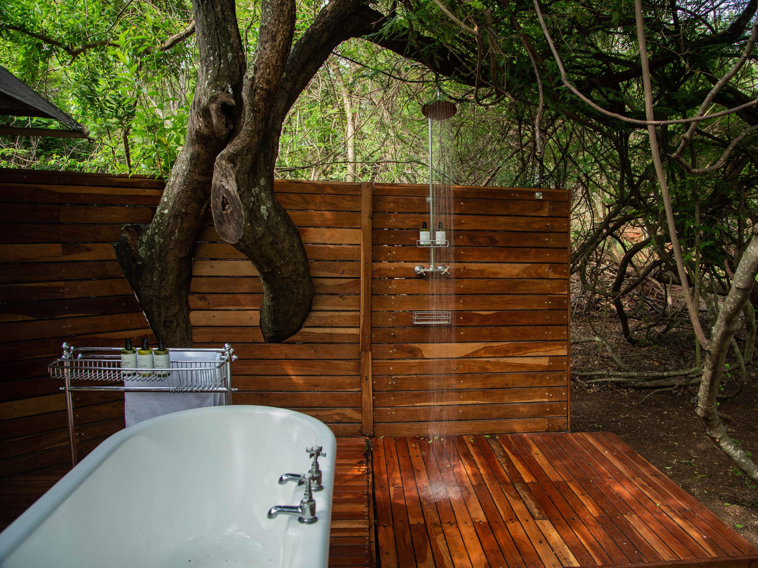 Een houten terras met een badkuip en douche.