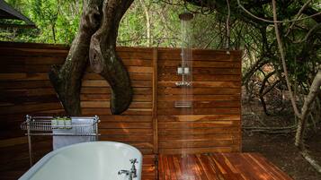 Een houten terras met een badkuip en douche.
