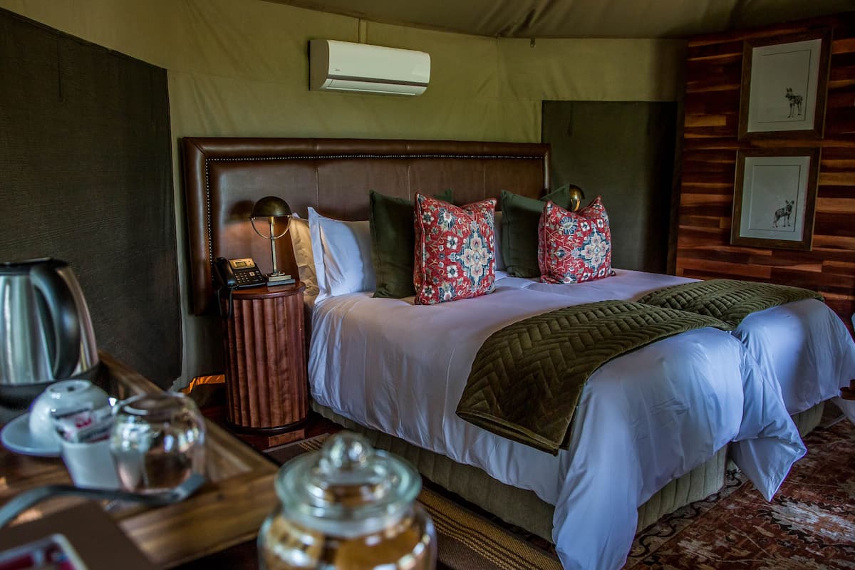 A hotel room with a large bed, a bedside table with a lamp, a coffee maker, and a jar of cookies.