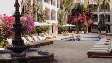 Una piscina al aire libre, sombrillas, sillones reclinables de piscina