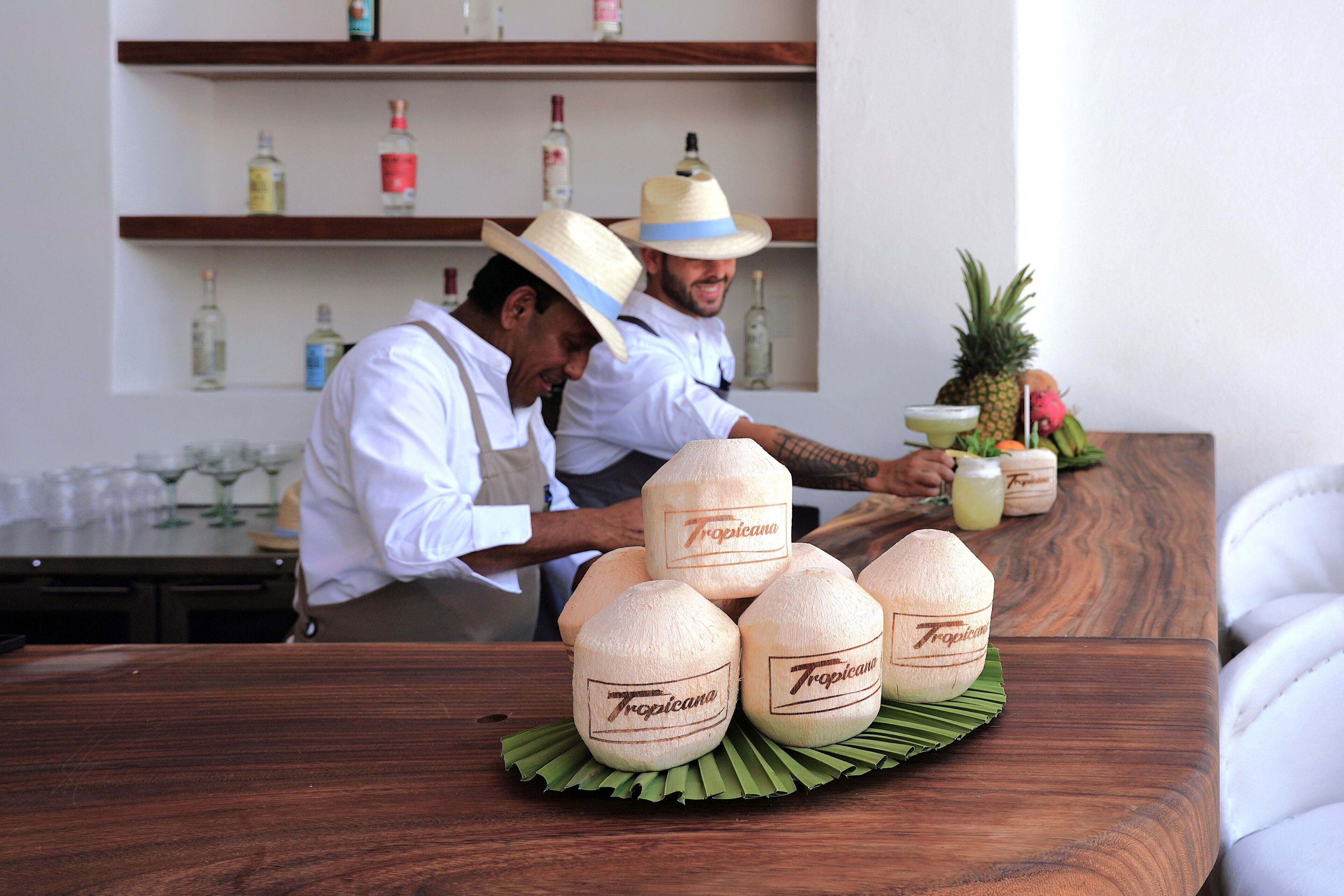 Una zona de bar con una mesa de madera que exhibe cocos con la etiqueta 'Tropicana'.