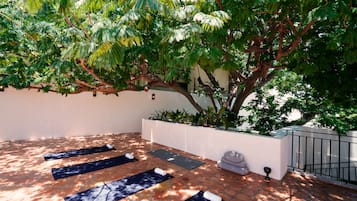 An outdoor yoga area with mats and a tree providing shade.