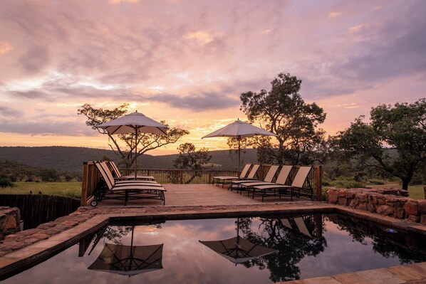 Una piscina al aire libre, sombrillas, tumbonas