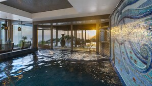 Een binnenzwembad met uitzicht op de zonsondergang, een mozaïekwand en zitgedeeltes.