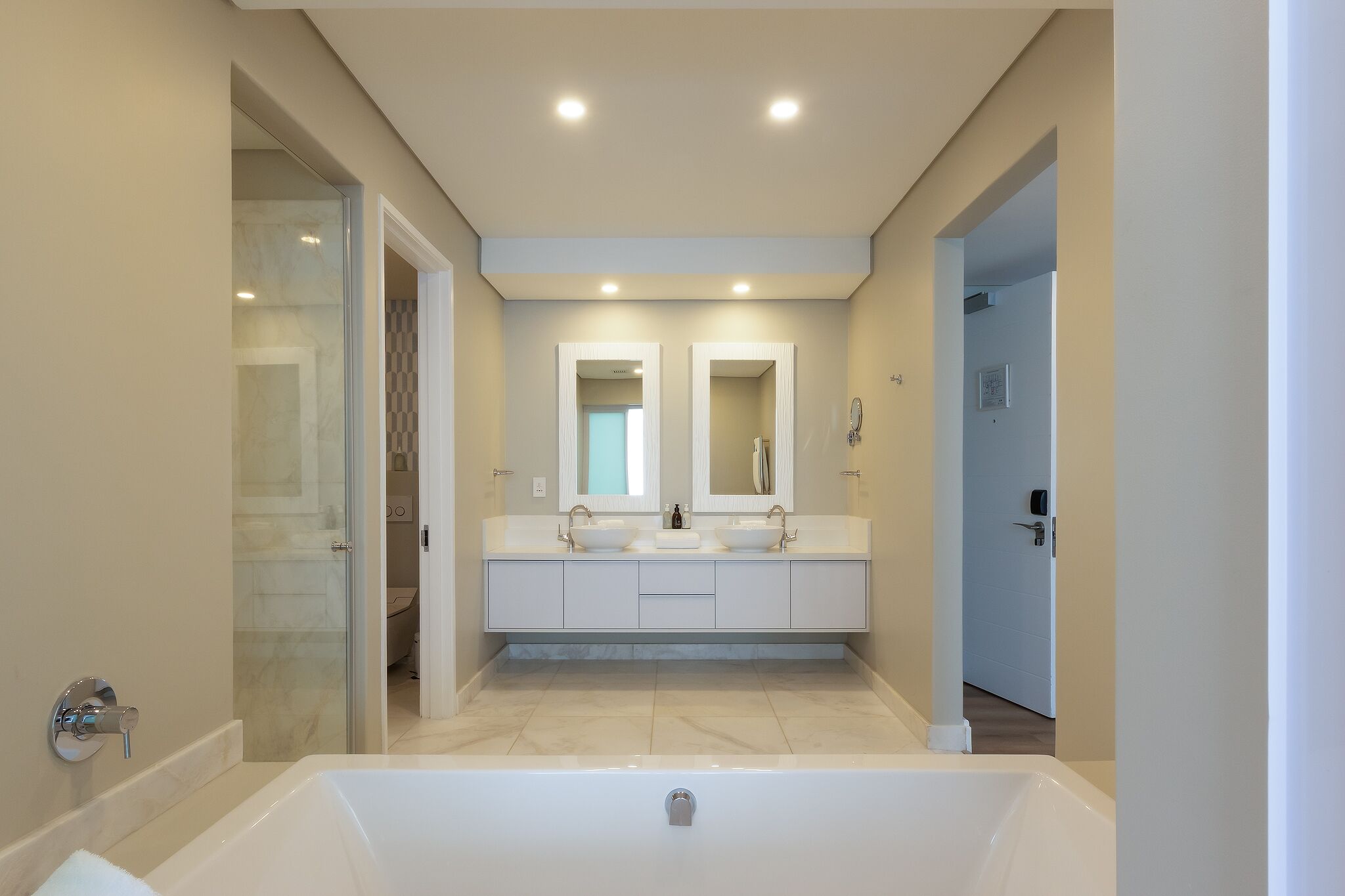 A modern bathroom with a bathtub, two sinks, and a glass shower enclosure.