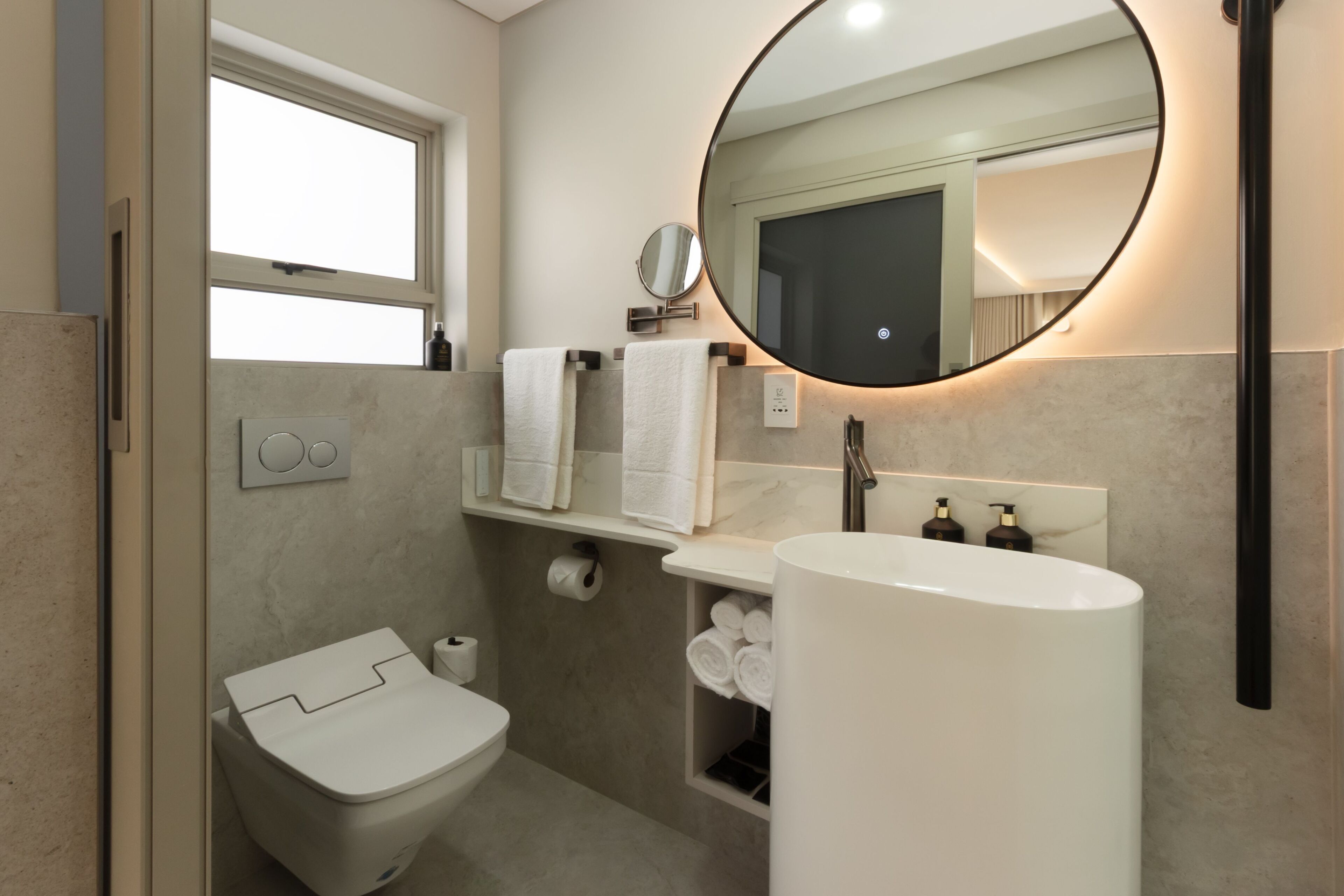 A modern bathroom with a toilet, sink, and mirror.