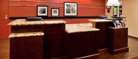 A reception desk with a red wall, framed pictures, and a welcome sign.