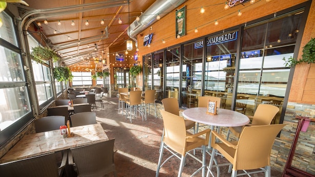 An indoor dining area with tables and chairs, large windows, and hanging plants. - Hampton Inn & Suites Aberdeen (Aberdeen)