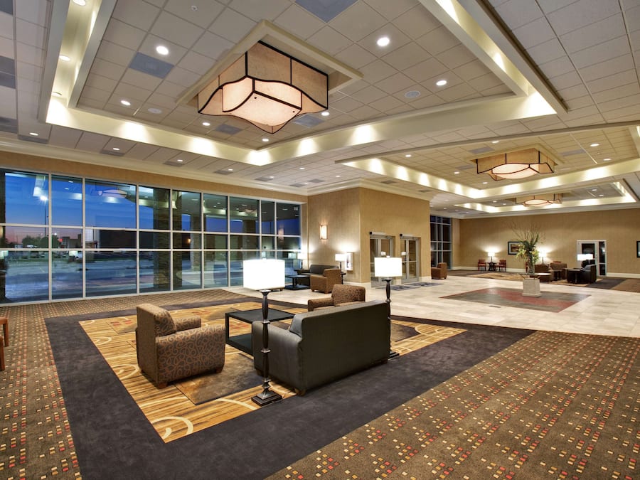 A spacious lobby with a large seating area, a reception desk, and a view of the outdoors through large windows.