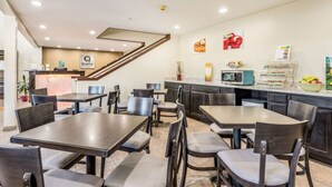 Un restaurant doté de plusieurs tables et chaises, d’un espace cuisine et d’une enseigne indiquant « Qualité ».