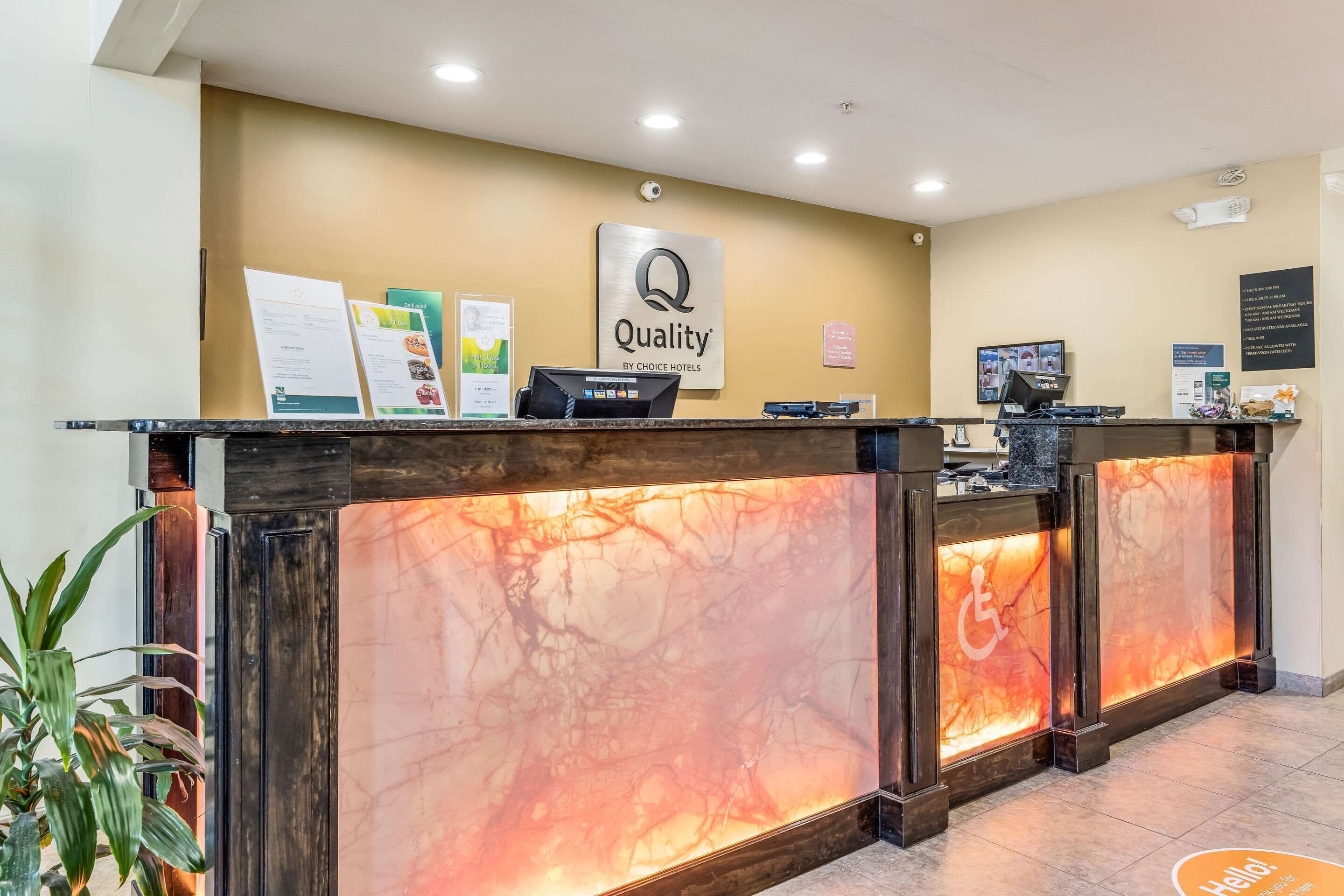 A hotel reception desk with a marble front, a sign reading "Quality by Choice Hotels," and a computer monitor.